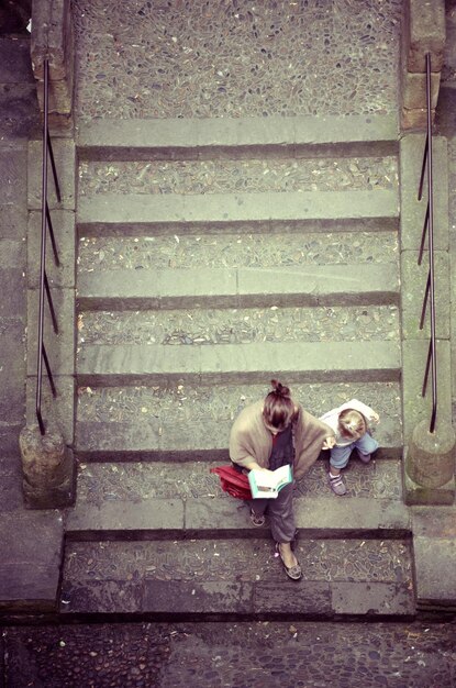 Foto hochwinkelansicht von mutter und tochter, die auf treppen sitzen