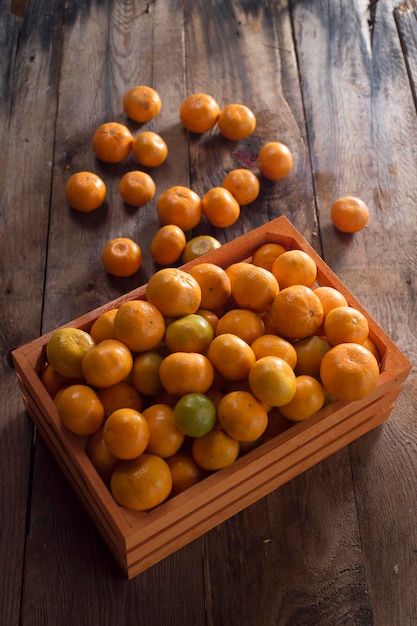 Hochwinkelansicht von orangefarbenen Früchten in einer Schachtel auf einem Holztisch