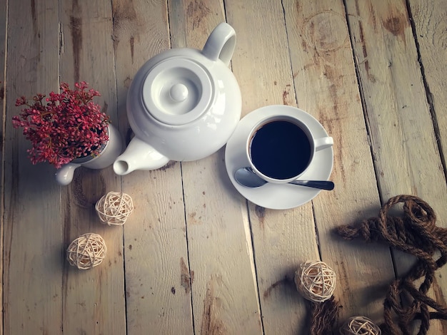 Hochwinkelansicht von schwarzem Kaffee durch Teekannen und Blumenvase auf dem Tisch