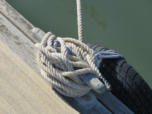 Hochwinkelansicht von Seil, das an einem Sonnentag am Pier am Fluss an einem Bollard gebunden ist