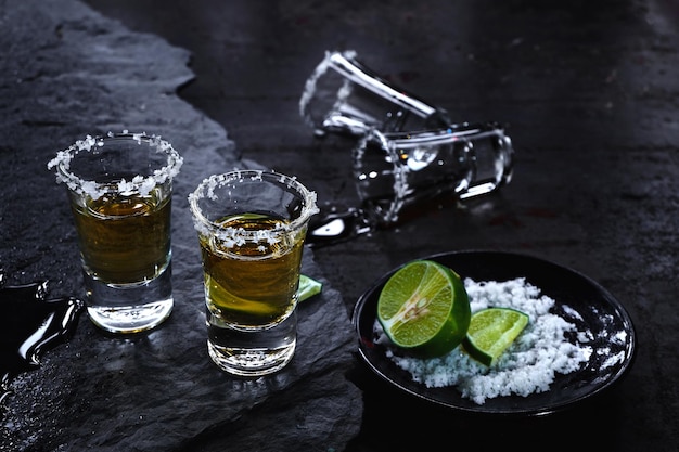 Hochwinkelansicht von Tequila-Aufnahmen mit Limette und Salz auf dem Tisch