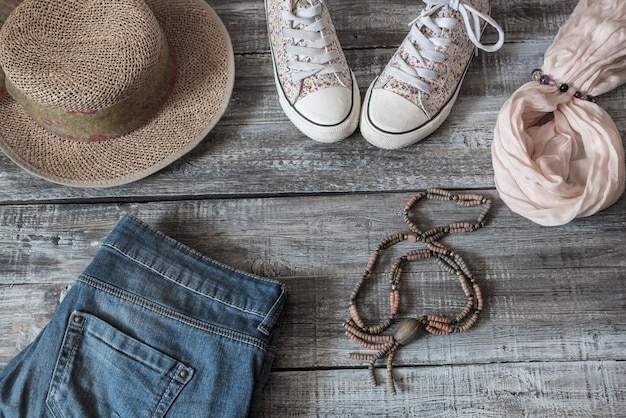 Hochwinkelansicht von Wickelhut mit Leinwandschuhen und Jeans auf Holzboden