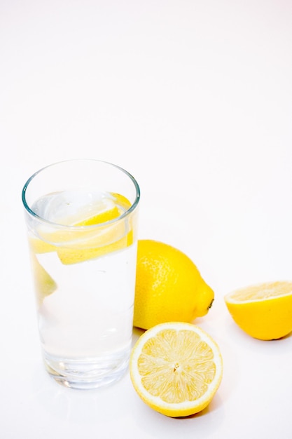 Hochwinkelansicht von Zitronenwasser im Glas auf weißem Hintergrund