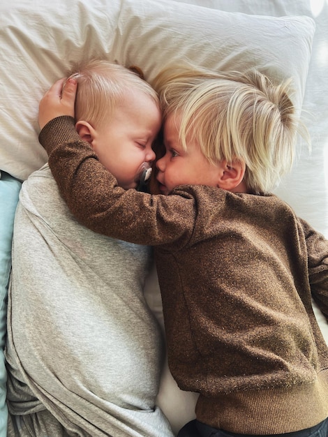 Hochwinkelansicht von zwei kleinen Kindern, die zu Hause auf dem Bett liegen