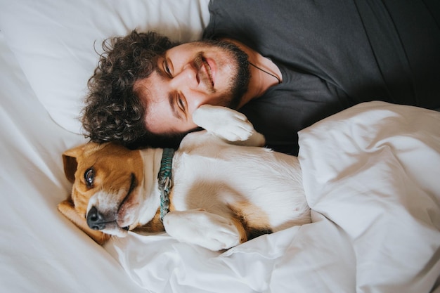 Foto hochwinkelporträt eines mannes mit hund im bett zu hause