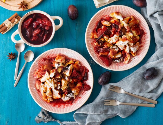 Hochwinklige Nahaufnahme kaiserschmarrn österreichisches Pfannkuchen-Dessert mit Pflaumen und Rosinen auf weißem Tisch