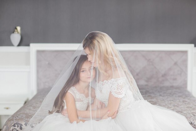 Hochzeit Braut im schönen Kleid sitzt auf dem Sofa drinnen im weißen Studio-Interieur wie zu Hause