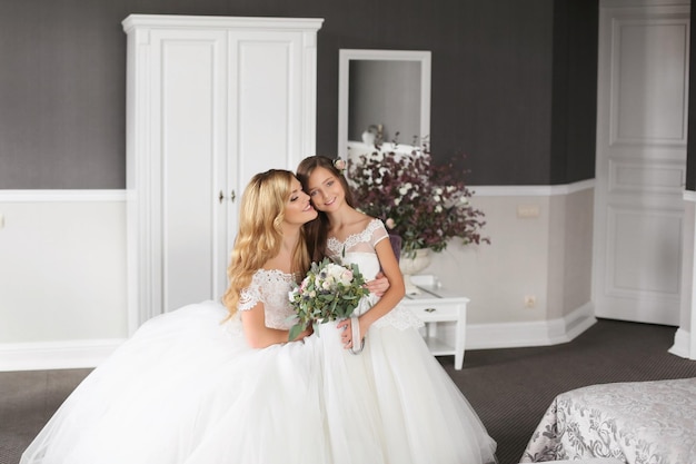 Hochzeit Braut im schönen Kleid sitzt auf dem Sofa drinnen im weißen Studio-Interieur wie zu Hause