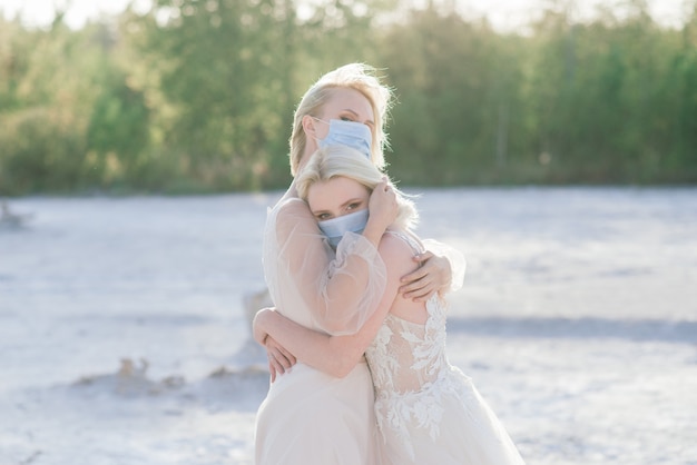 Hochzeit eines lesbischen Paares auf weißem Sand, Masken tragen, um die Epidemie COVID-19 zu verhindern