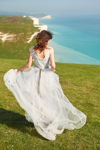 Hochzeit Hochzeit am Meer. Eine junge Braut geht entlang einer Klippe am Meer.