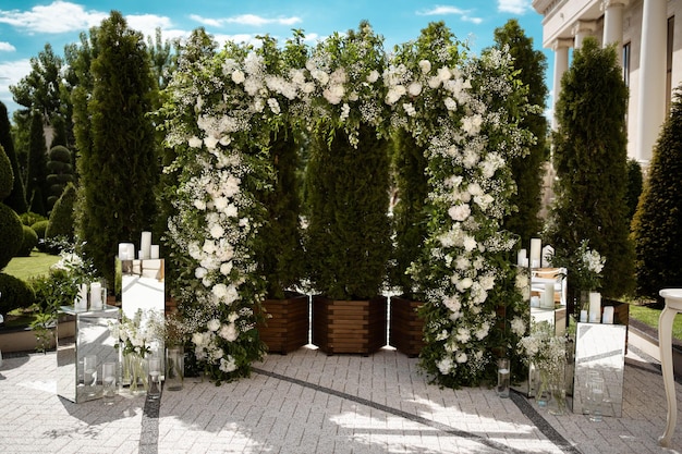 Hochzeit Hochzeitszeremonie Bogen Mit weißen Blumen geschmückter Bogen, der im Wald im Bereich der Hochzeitszeremonie steht