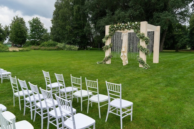 Hochzeit im Freien eines Parks Hochzeitsbogen auf dem Feld Chiavari-Stühle werden ausgestellt Seitenansicht