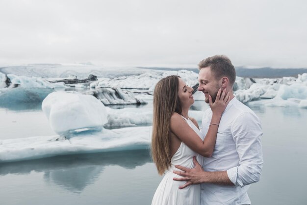 Hochzeit in Island. Ein Mann und ein Mädchen in einem weißen Kleid umarmen sich, während sie auf einem blauen Eis stehen