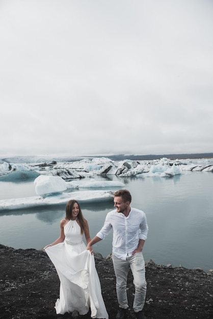 Hochzeit in Island. Ein Mann und ein Mädchen in einem weißen Kleid umarmen sich, während sie auf einem blauen Eis stehen