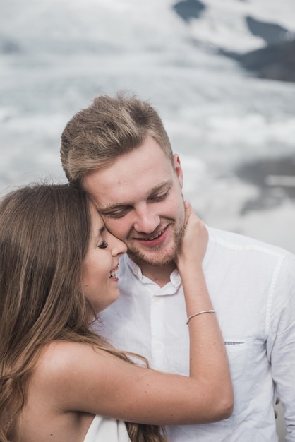 Hochzeit in Island. Ein Mann und ein Mädchen in einem weißen Kleid umarmen sich, während sie auf einem blauen Eis stehen