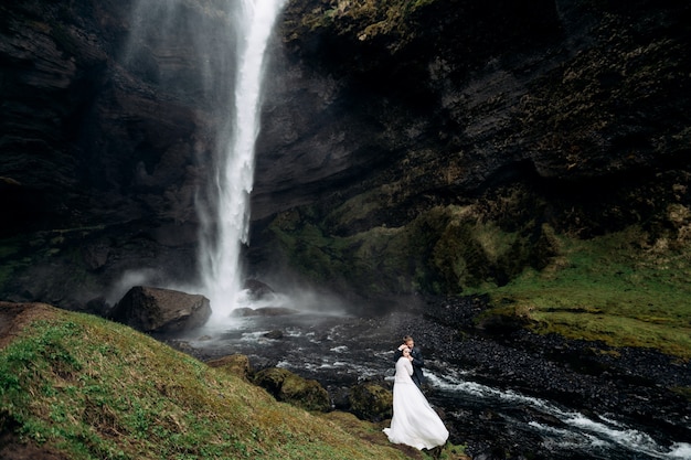 Hochzeit in Island in der Nähe des Wasserfalls Kvernufoss Hochzeitspaar steht in der Nähe des Wasserfalls