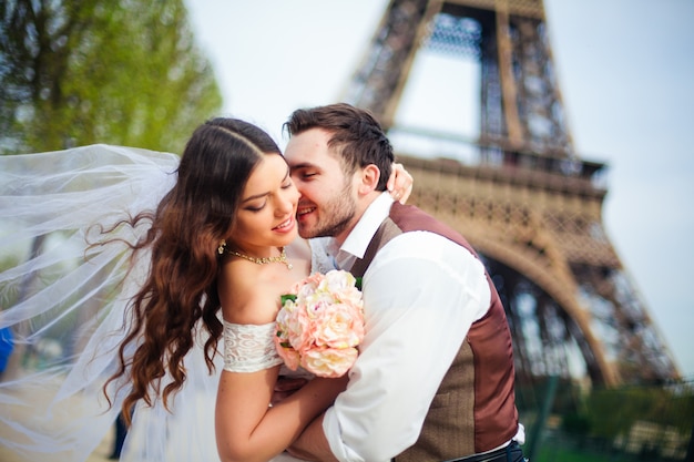 Hochzeit in Paris. Glückliches gerade verheiratetes Paar, das nahe Eiffelturm umarmt