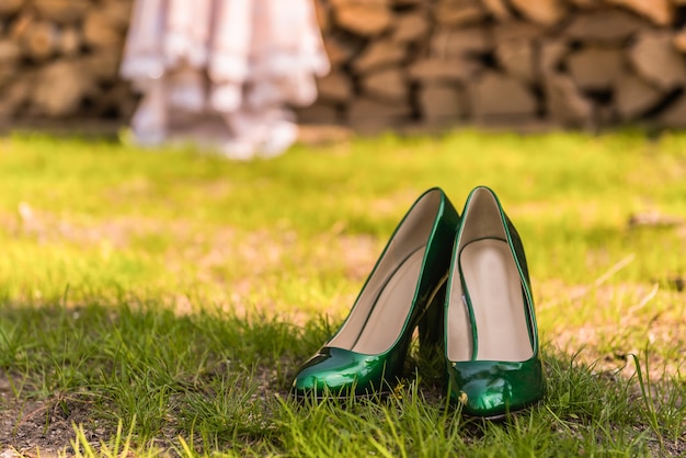 Hochzeit smaragdgrüne Brautjungfernschuhe auf dem grünen Gras auf dem Hintergrund des Kleides