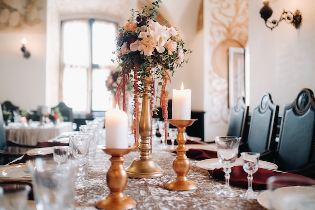 Hochzeit Tischdekoration mit Blumen auf dem Tisch im Schloss, Tischdekoration zum Abendessen bei Kerzenschein.