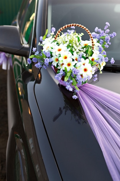 Hochzeitsautokorb mit Blumen dekorieren.