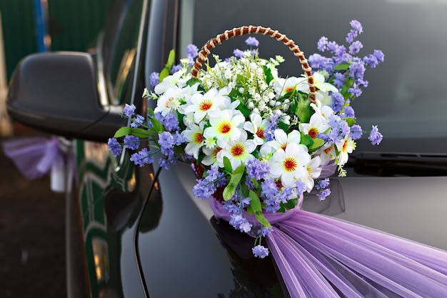 Hochzeitsautokorb mit Blumen dekorieren.