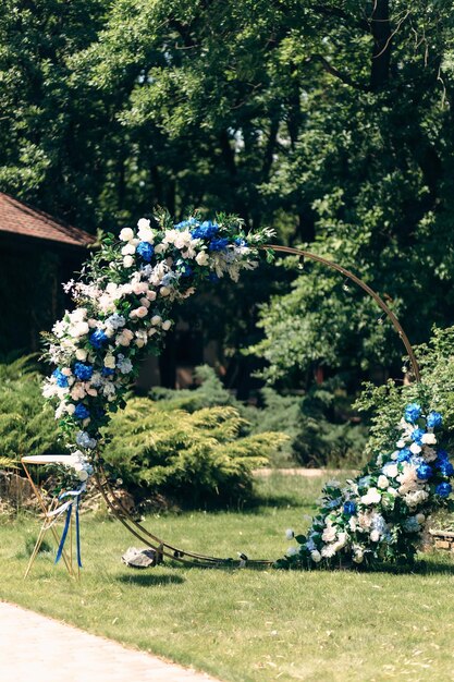 Hochzeitsbänke mit Gästen und Blumenbogen für die Zeremonie im Freien