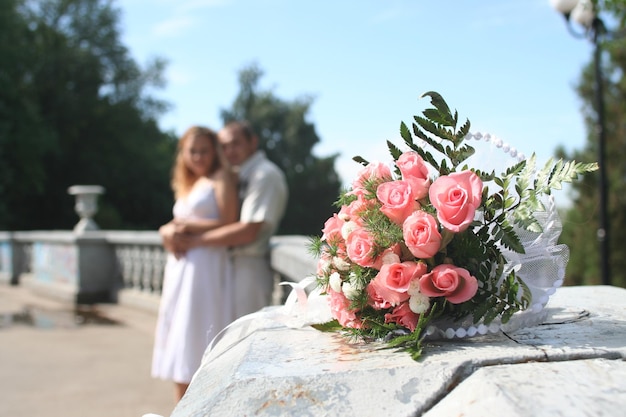 Hochzeitsblumenstrauß im Vordergrund Braut und Bräutigam im Hintergrund
