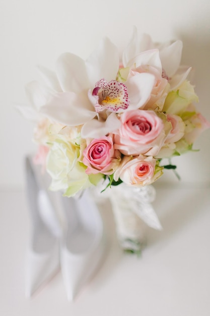 Hochzeitsblumenstrauß mit Orchideen und Rosen und weddind Brautschuhen auf weißem Hintergrund im Kunststil