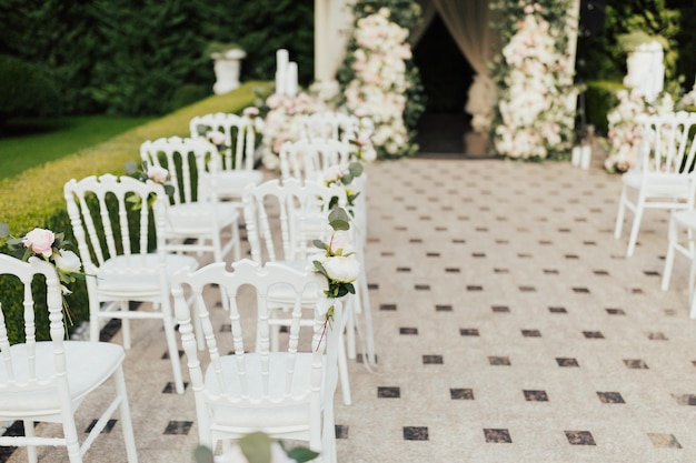 Hochzeitsbogen mit Blumen und Stühlen sind mit weißen und rosa Blumen geschmückt