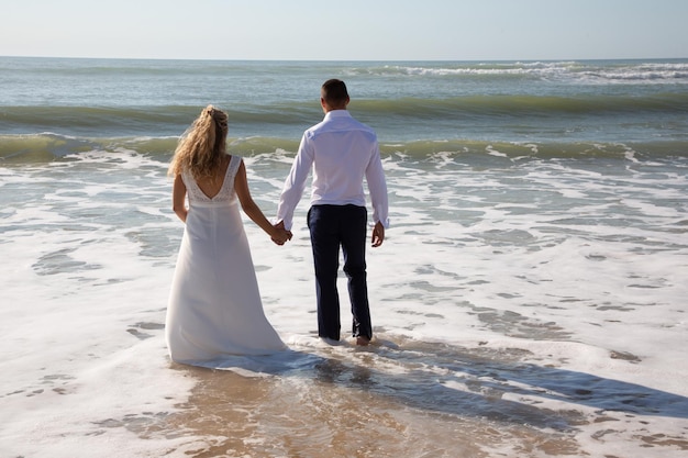 Hochzeitsbraut und -bräutigam auf einem Strandfuß im Meerwasser