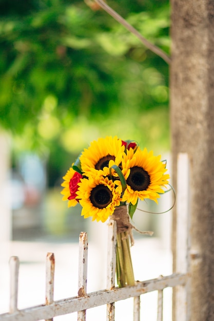 Hochzeitsbrautstrauß von Sonnenblumen auf einer Metallzaunhochzeit