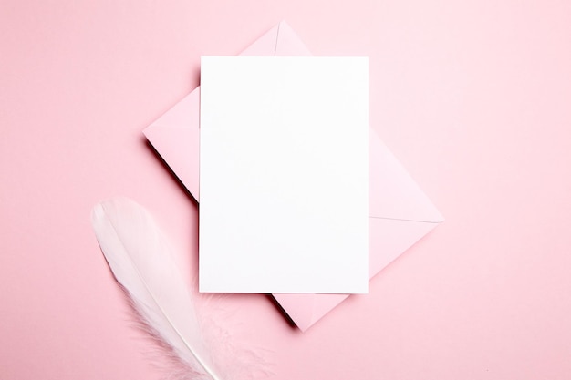 Foto hochzeitseinladung mit leerer karte oder valentinstagsbrief mit rosafarbenem umschlag und weißer feder
