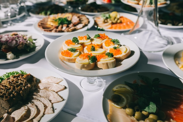 Hochzeitsfesttabelle mit verschiedenen Tellern und Brot mit rotem Kaviar.