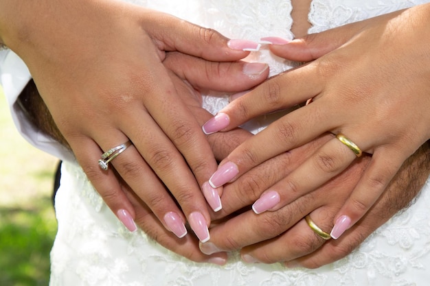 Hochzeitsfinger goldene Ringe auf den Händen des Brautbräutigams auf weißem Kleiderhintergrund