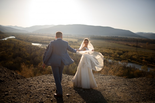 Hochzeitsfoto-Sitzung der Braut und des Bräutigams in den Bergen. Fotoshooting bei Sonnenuntergang.