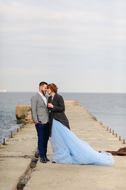 Hochzeitsfoto-Sitzung eines Paares an der Küste. Blaues Hochzeitskleid auf der Braut.