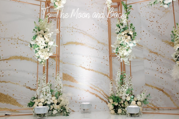 Hochzeitsfotozone verziert mit weißen Blumen und grünen Blättern mit einer Inschrift zum Mond und