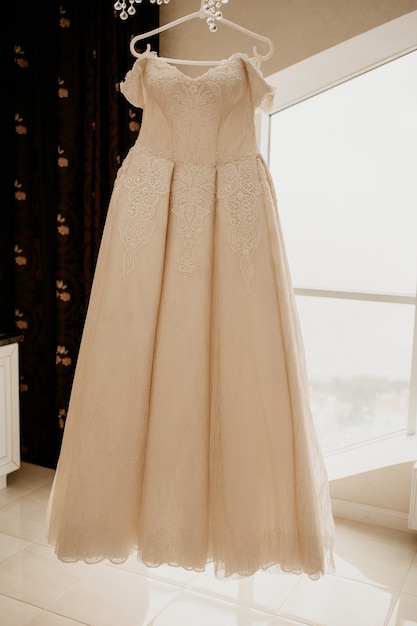 Hochzeitskleid auf Kleiderbügel im Bräutigamzimmer. An ihrem Hochzeitstag.