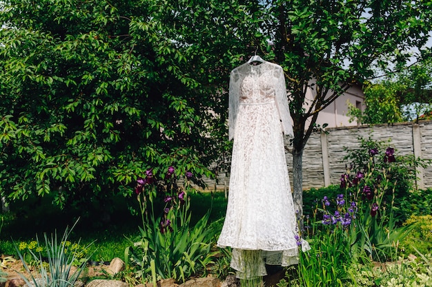 Hochzeitskleid der Braut, die im grünen Garten hängt