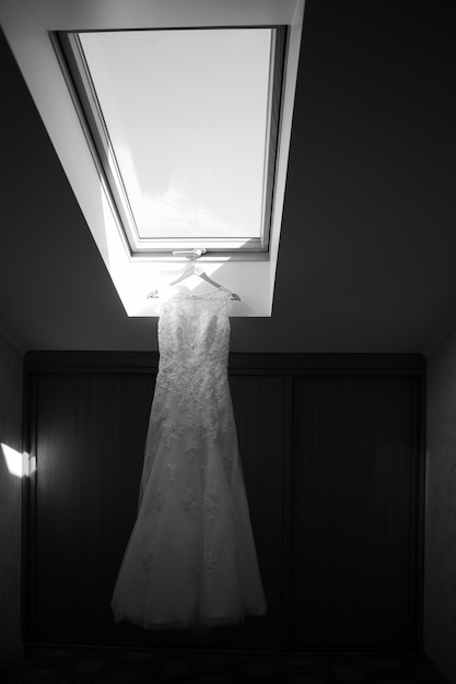 Hochzeitskleid hängt am Fenster im Hotelzimmer