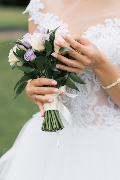 Hochzeitsmaniküre und Brautstrauß in der Hand
