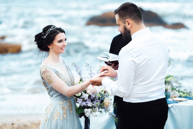 Hochzeitspaar am Meer mit einem Priester