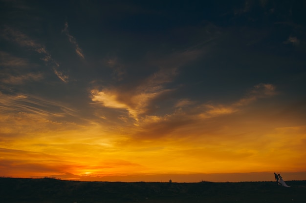 Hochzeitspaar auf dem Hintergrund des Sonnenuntergangs