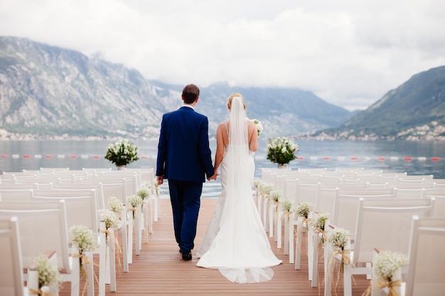 Hochzeitspaar bei der Rückansicht der Hochzeitszeremonie. Berge und Meereshintergrund in Montenegro