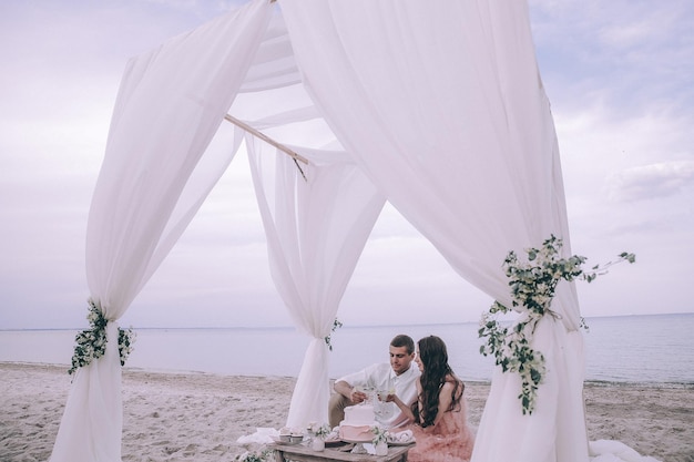 Hochzeitspaar, Bräutigam, Braut mit dem Blumenstrauß, der nahe Meer und blauem Himmel aufwirft