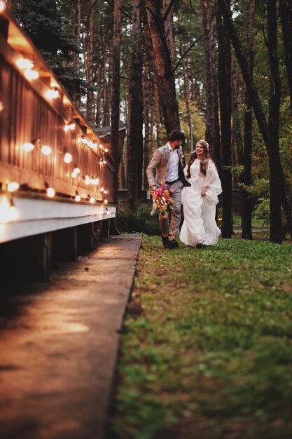 Foto hochzeitspaar läuft an bäumen vorbei