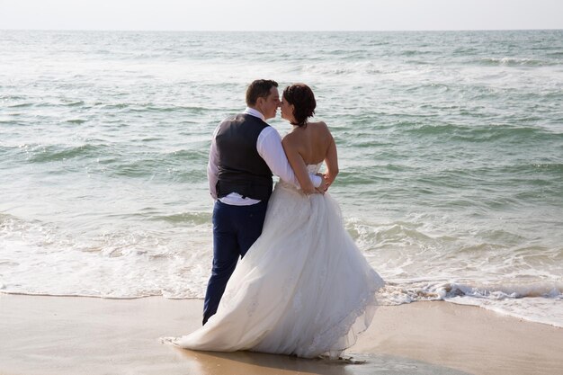 Hochzeitspaar mit Blick in die Zukunft am Strand