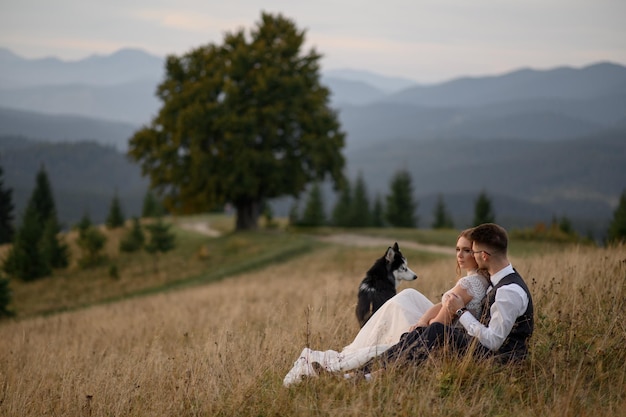 Hochzeitspaar mit Hund in den Bergen bei Sonnenuntergang romantischer Abend in den Bergen