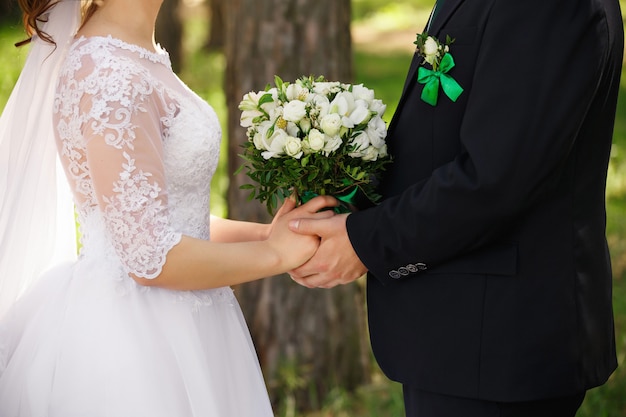 Hochzeitspaar mit Strauß frischer Blumen, Braut und Bräutigam Händchen haltend, Jungvermählten verliebt nach Hochzeitszeremonie