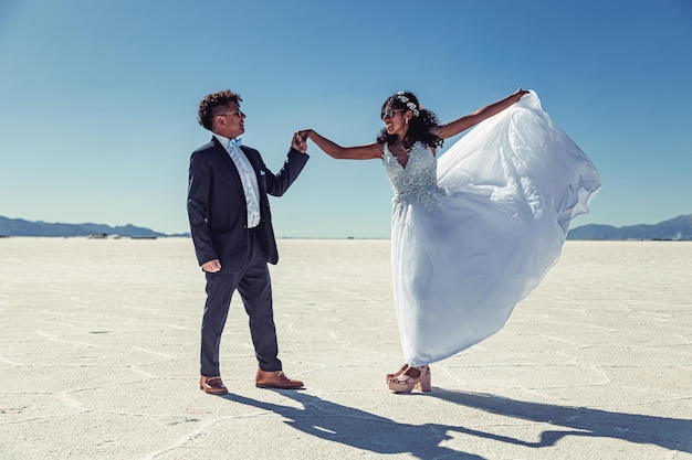 Hochzeitspaar posiert in weißer Landschaft mit Kleid und Anzug